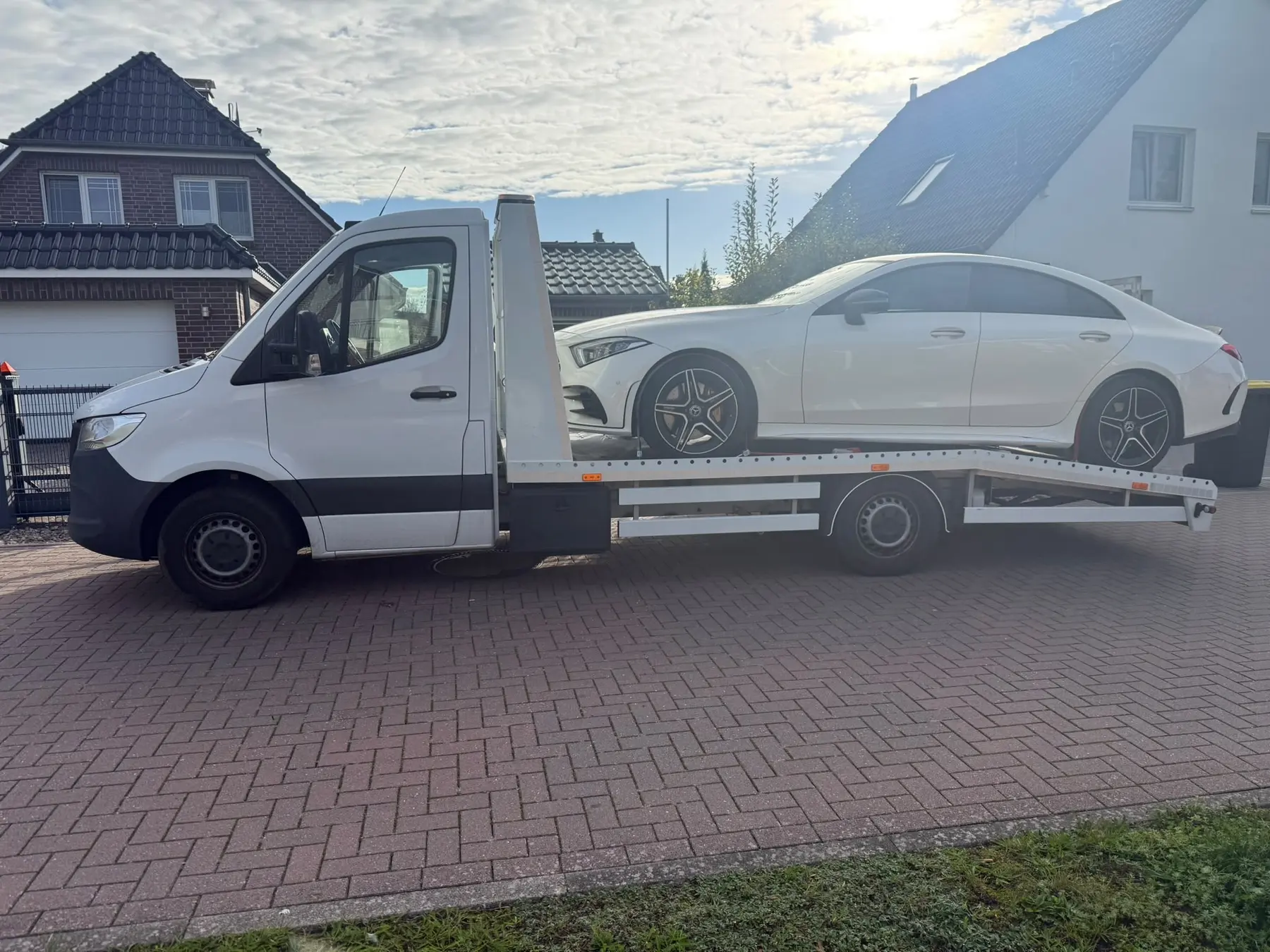 Weißer Mercedes CLA auf dem BLITZ-Abschleppwagen vor einem Wohnhaus